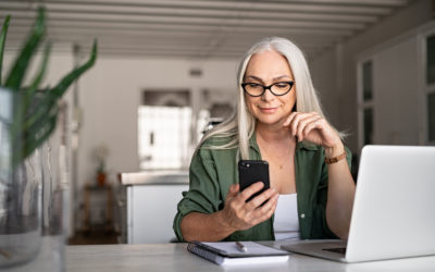 Happy senior woman using mobile phone while working at home with